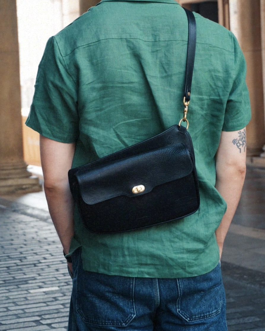 Black leather crossbosy bag with clasp and zip, won on the back.