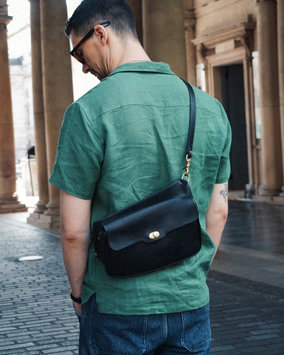 Black leather crossbosy bag with clasp and zip, won on the back.