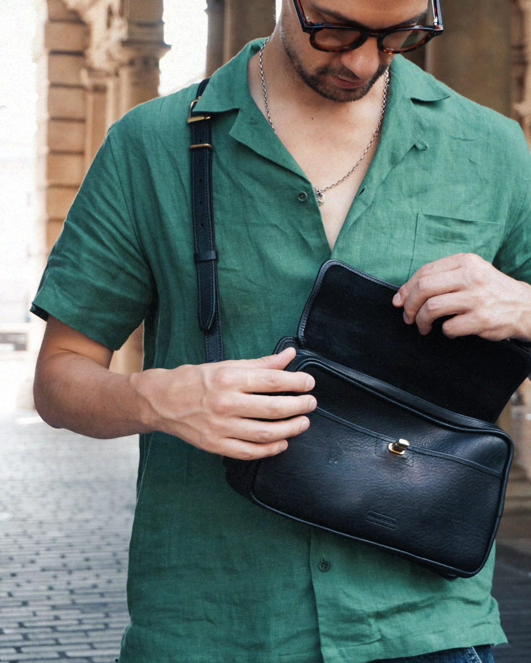 Black leather crossbosy bag with clasp and zip.